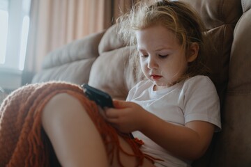 Obraz premium A 4-year-old girl naturally engages with a tablet, exploring digital education and games. Authentic 