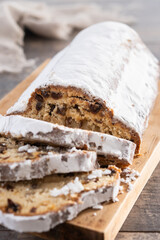 Traditional Christmas Stollen with Raisins and Powdered Sugar on wooden table	