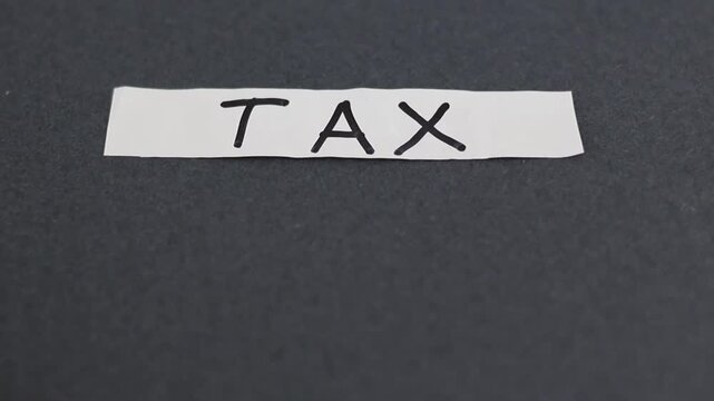 Un primer plano de un papel blanco con la palabra impuesto en un fondo gris oscuro