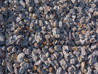 Gabion stone wall construction close up. New stone fence in wire grid, iron cage with rocks