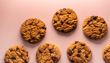 Food flat lay showing seven textured chocolate chip cookies. The lighting is soft, emphasizing the rich brown tones and sweet indulgence of the treats.
