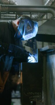 A worker welds metal in a protective helmet. Heavy industry and metallurgy. Professional at work. Industrial electrogas welding. 25 fps 6k footage.