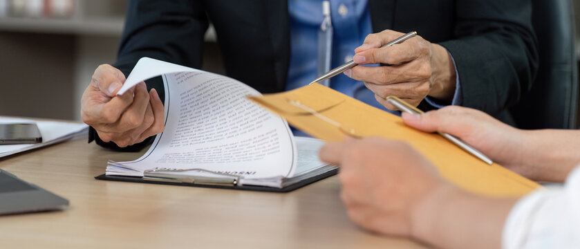 Business Agreement. Professionals reviewing documents and discussing contract details.