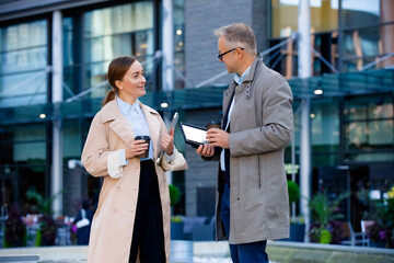 Happy business partners connect outdoors. Diverse professionals discuss work in an urban setting....