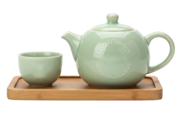 Pastel green ceramic teapot and cup on wooden bamboo serving tray on isolated background