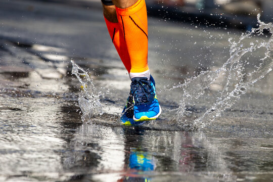 Runner legs in compression socks running water on road