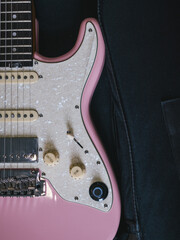 Close-up of a pink electric guitar with a pearlescent pickguard. This image showcases the details of a stylish pink electric guitar, perfect for music enthusiasts and designers