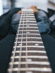 Close-up of a guitar fretboard with strings and frets in sharp focus. This image showcases the intricate details of a guitar's fretboard, highlighting the strings and frets
