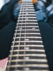 Close-up of a guitar fretboard with strings and frets in focus. This image showcases the intricate details of a guitar's fretboard, highlighting the strings and frets