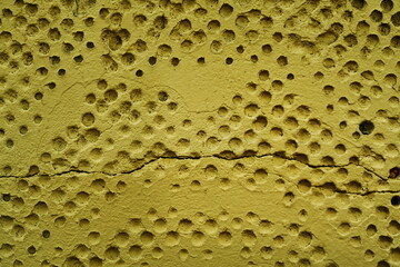 Mur ancien avec alv&eacute;oles rondes peint en jaune.