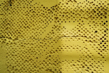 Mur ancien avec alv&eacute;oles rondes peint en jaune.
