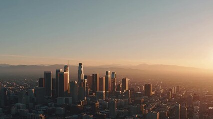 Breathtaking aerial view of a bustling metropolitan skyline at golden hour, showcasing modern skyscrapers against a serene, hazy mountain backdrop as the sun dips below the horizon