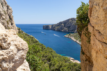 Scenic view of Calanques National Park in Marseille featuring turquoise Mediterranean water and boats framed by limestone cliffs and trees