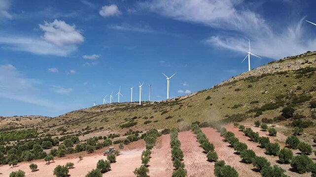TRACTOR ARANDO CAMPO DE OLIVOS ENTRE MOLINOS EOLICOS