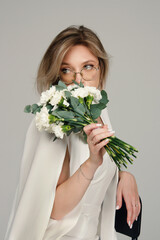 Portrait of a girl in a white suit holding flowers. Female portrait.	