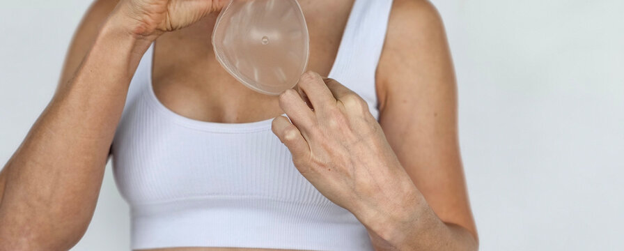 Woman demonstrating the adjustment of a silicone insert in a sports bra for added shape and support concept