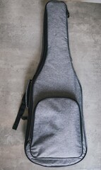 Gray acoustic guitar case on a textured gray background. This image showcases a gray guitar case, perfect for musicians on the go, set against a neutral backdrop