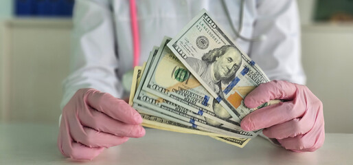 Medical professional holding cash in a clinic while wearing gloves during a consultation in a...