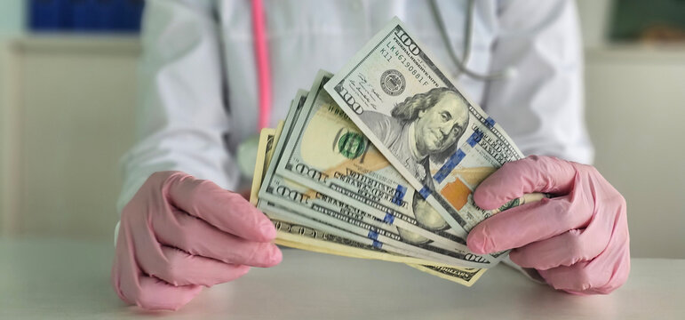 Medical professional holding cash in a clinic while wearing gloves during a consultation in a healthcare