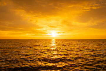 Obraz premium Nature sky breathtaking golden sunset over a calm ocean, with the entire sky and water bathed in brilliant shades of yellow and orange. Streaky clouds enhance the dramatic display of light 