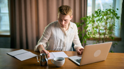 Man working with laptop and coffee cup on large office desk. Concept of business workflow, productivity coaching, professional training materials, and organized office routine visuals.
