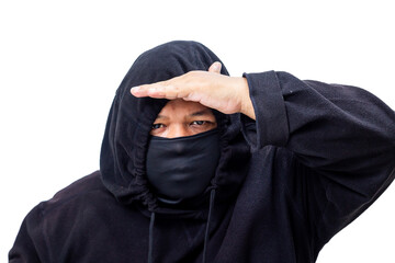 A mysterious man dressed in a black hoodie and face mask shields his eyes while looking into the distance like a modern ninja scout on a white background © agung