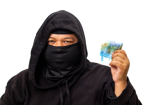 Enigmatic person in a black hoodie and mask displays a stack of money, suggesting themes of financial secrecy, illegal transactions, or undisclosed wealth - Powered by Adobe