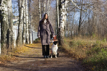 A young Indian woman stands on a woodland trail with her dog by her side, enjoying a peaceful day in nature