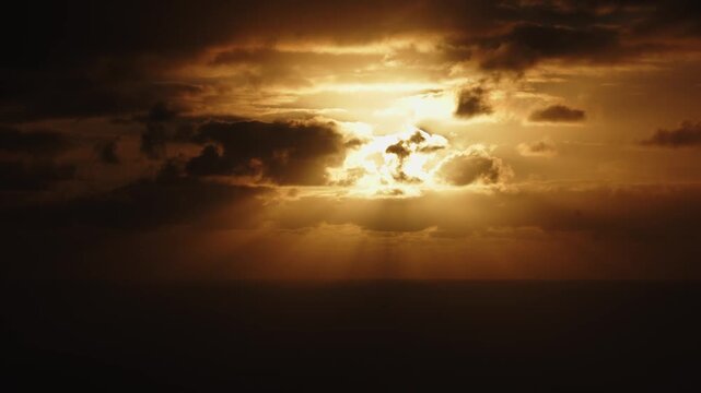 Dramatic sunset scene with golden rays breaking through clouds over the ocean, showcasing a gradual transition of light and shadow, camera pans across the horizon