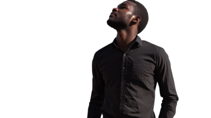 Man in black shirt looking up against a white background during bright daylight.