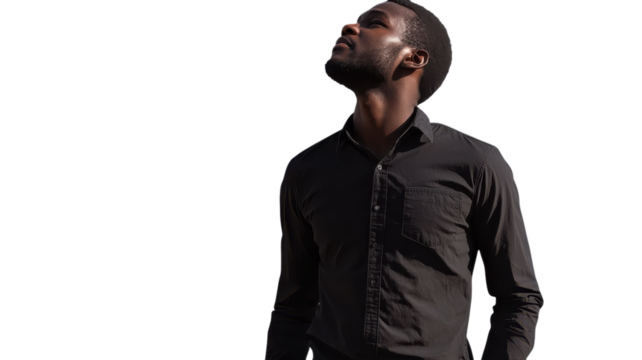 Man in black shirt looking up against a white background during bright daylight.
