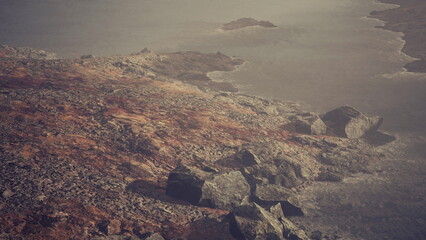 A serene coastal view showcases rugged rock formations and gentle waves lapping at the shore as twilight settles in, creating a peaceful atmosphere.