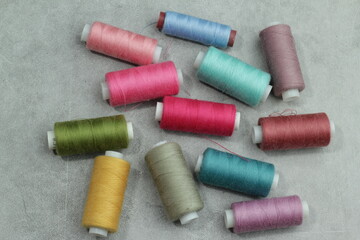 Set of different colorful sewing threads on light blue background, flat lay. With space for text.