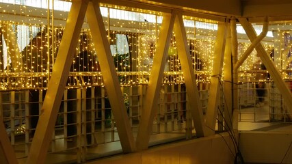 Timelapse Person Walking Through Illuminated Bridge Passage: Motion Blur Figure on Modern Walkway with Golden String Lights Night Scene - Powered by Adobe