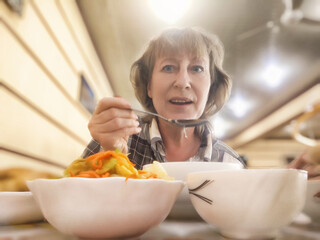 Mature blonde woman enjoying a delicious meal while blogging about her lifestyle in a cozy...