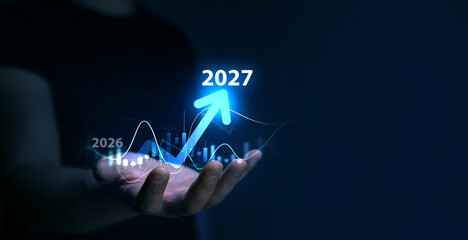Business plan for increase in 2027 year.Development to success and motivation in new year 2027. Business person draws increase arrow graph corporate future growth year 2026 to 2027. 
