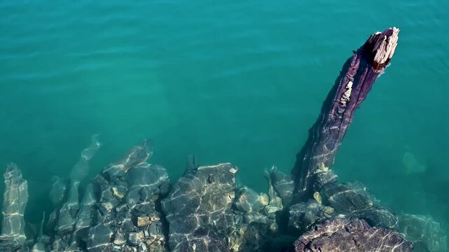 A closeup view of ripples moving across the blue water of Hazorchashma Lake, the seventh lake of the Seven Lakes in the Fann Mountains near Panjakent, Tajikistan, with a branch in the frame.