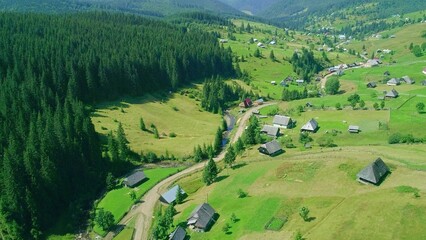 Summer village in valley view from drone with green field