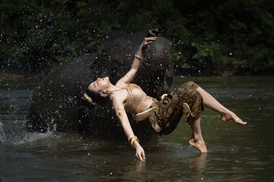 Elegant dancer river elephant splash water traditional costume gold jewelry cultural nature forest graceful balance motion serenity mythic ceremony ritual heritage Asia wildlife