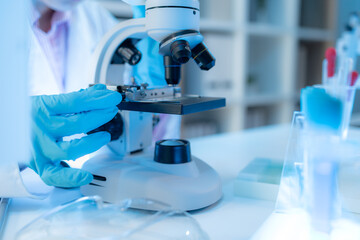 A chemistry researcher in a laboratory surrounded by scientific equipment and test tubes,...