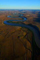 Aerial view of a meandering river through a dry landscape under a clear blue sky