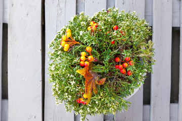 Artificial flowers and cherry blossoms in a pot on white wooden planks. Top view.