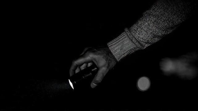 Hand holding a flashlight in the dark, searching for something lost.