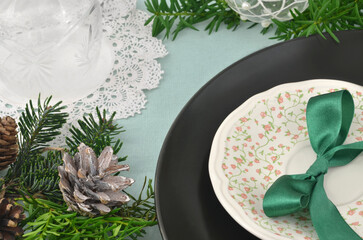 Christmas table setting with christmas decorations: green bow, crocheted doily, a saucer painted...