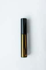 Eyelash extension oil in a transparent tube with a brush. White background.