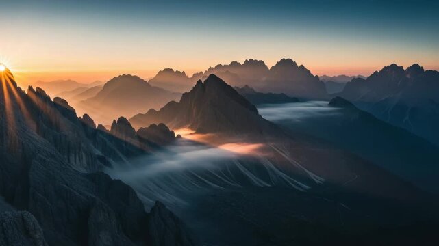 Majestic panoramic view of a sunrise over the alpine peaks with golden light rays. A beautiful sequence showing the sun rising above the misty valleys and rugged mountains - Powered by Adobe