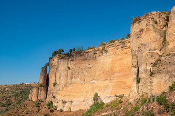 View of cliff with unique natural rock arch and Tajo de Ronda gorge in Ronda at sunny day, Andalusia, Spain. Travel destination.
