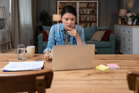 Focused business expert working from home reviewing detailed analytics reports and planning innovative marketing strategies on laptop providing professional consulting insights for digital growth