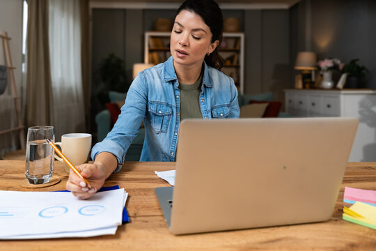 Focused business expert working from home reviewing detailed analytics reports and planning innovative marketing strategies on laptop providing professional consulting insights for digital growth - Powered by Adobe