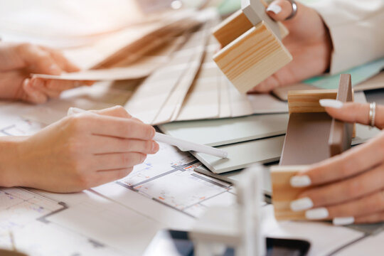 Hands discussing client and designer architectural design with color swatches and scale models